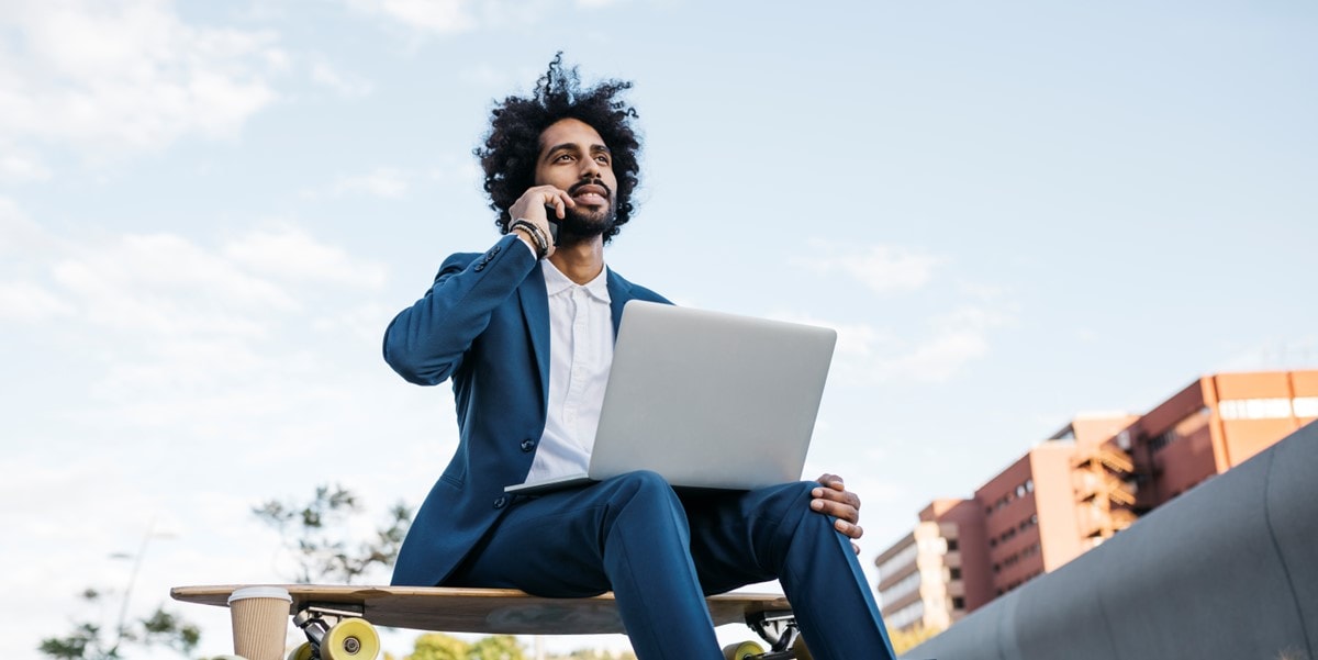 man sitting outside with phone and laptop