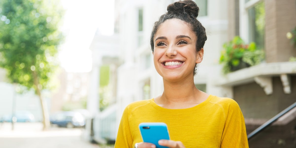 smiling woman outside holding phone