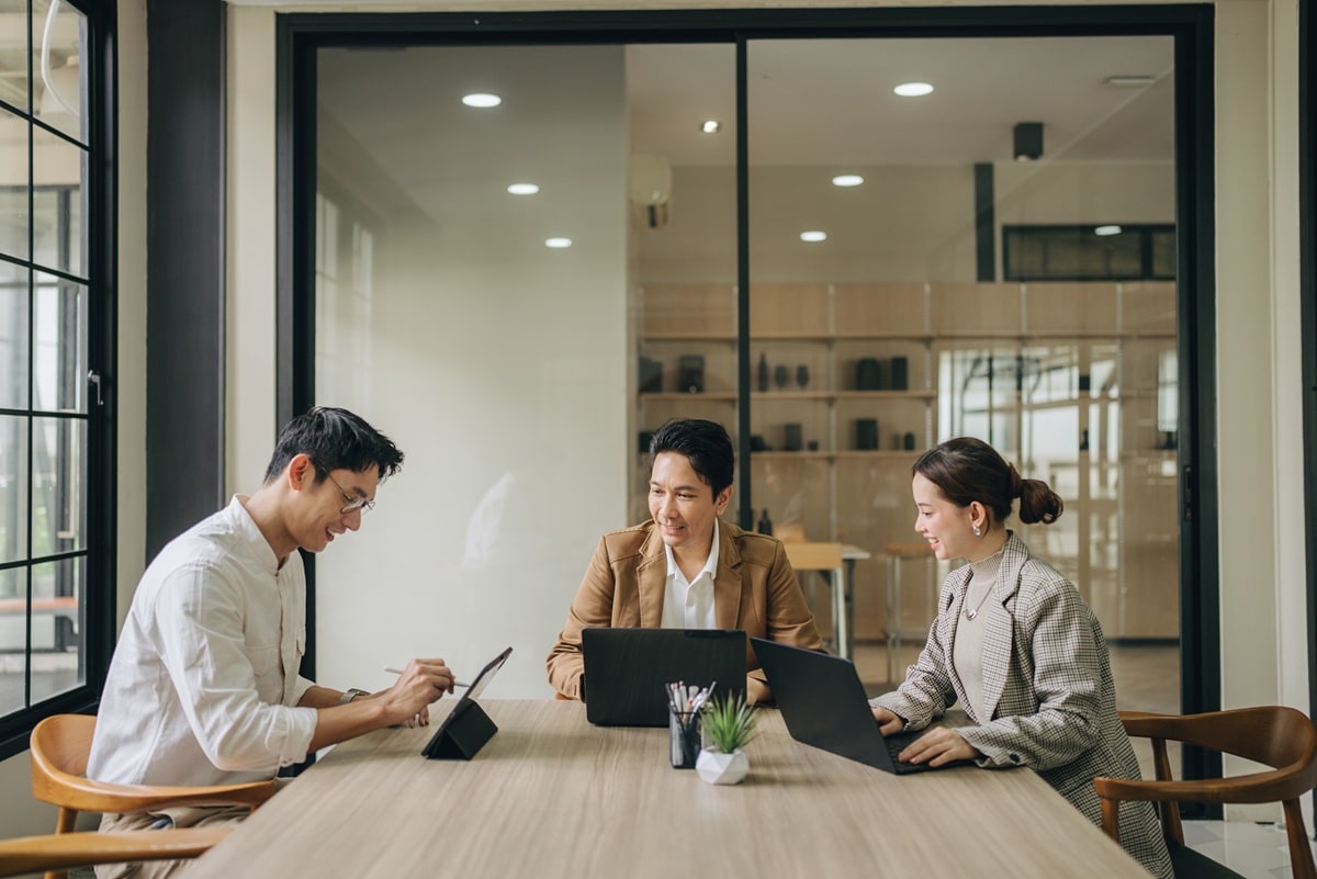 Three people sitting around a large meeting table