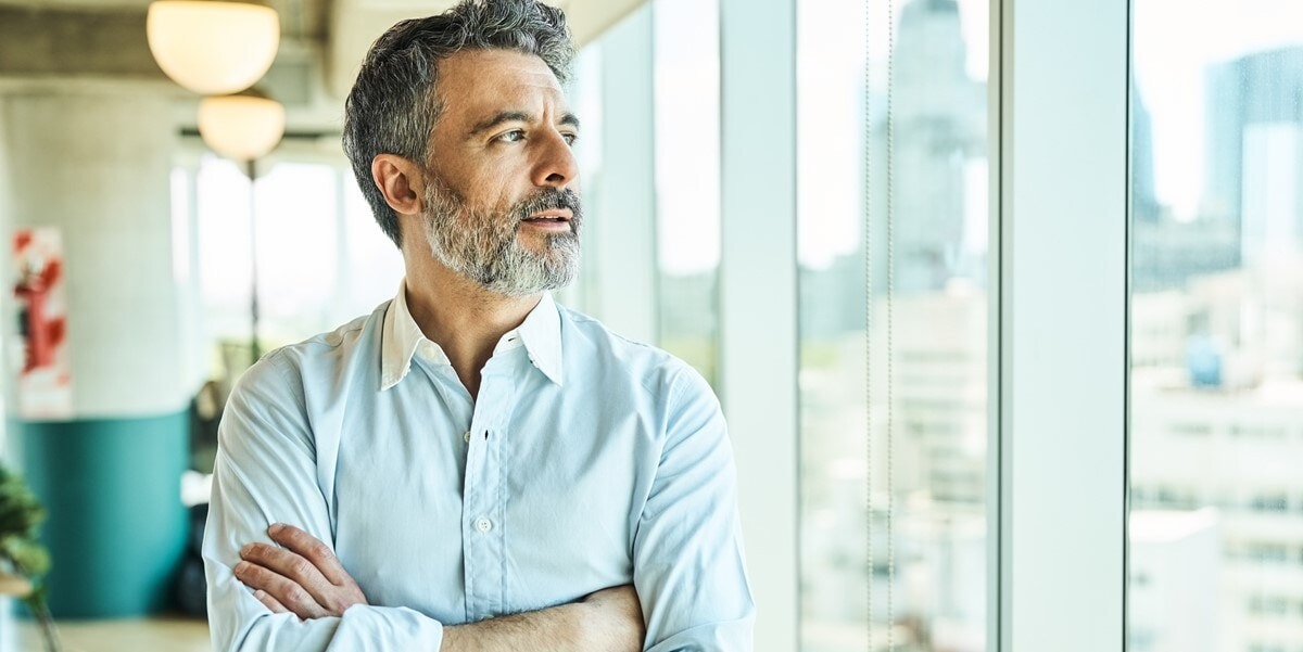 professional man in office looking out window