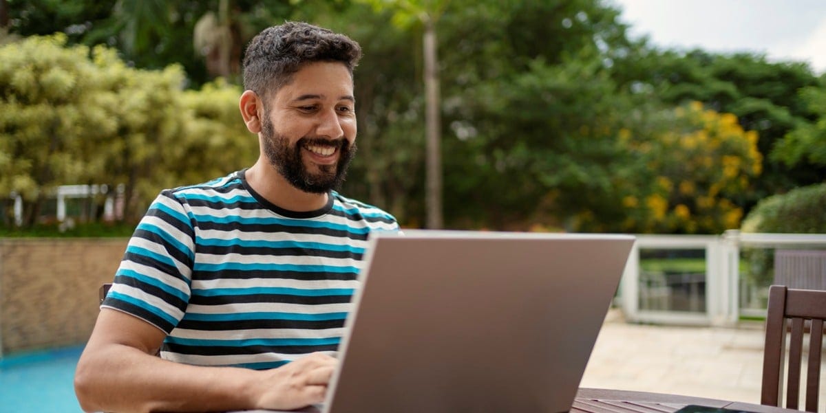 man working remotely, using laptop at table outdoors