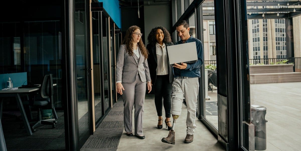 3 professionals in the office walking down hallway